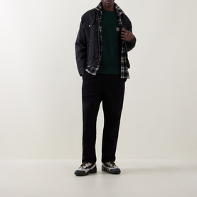 Model wearing Carhartt Crew Neck T in Dark Scarab green, styled with dark overshirt, plaid shirt, black trousers and trail trainers.
