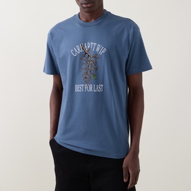 Model wearing Carhartt Crew Neck T in Icesheet blue with graphic print, styled with black trousers.