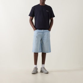 Model wearing Carhartt Crew Neck T in Dark Navy with small chest logo, styled with light blue denim shorts and grey trainers.
