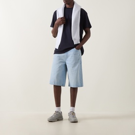 Model wearing Carhartt dark navy crew neck T-shirt with white towel draped over shoulders, styled with light blue denim shorts and grey trainers.