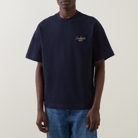 Model wearing Carhartt Signature Script Logo T-Shirt in dark navy, with gold embroidered chest logo, crew neck and short sleeves, styled with blue