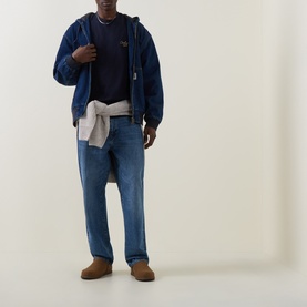 Model wearing Carhartt Signature Script Logo T-Shirt in Dark Navy, styled with blue denim jacket, mid-wash jeans and tan suede shoes
