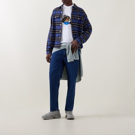 Model wearing Carhartt white crew neck T-shirt, styled with blue plaid overshirt, navy trousers, and grey trainers.