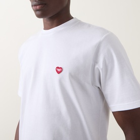 Model wearing Carhartt white crew neck T-shirt with small red heart logo embroidery on chest, 100% cotton.