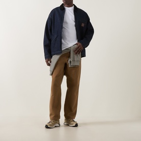Model wearing Carhartt white crew neck T-shirt, styled with navy jacket, tan trousers, and grey trainers.