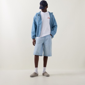 Model wearing Carhartt white crew neck T-shirt with light blue zip jacket, denim shorts, grey slides and navy cap.