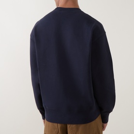 Model wearing Carhartt dark navy cotton sweatshirt, rear view, styled with tan trousers