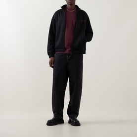 Model wearing Carhartt black zip-through sweat jacket, styled with burgundy top and dark trousers