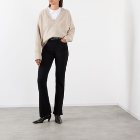 Model wearing FRAME DENIM Reboot Bootcut Jeans in black, high-rise fit, styled with a beige V-neck knit and black heeled boots.
