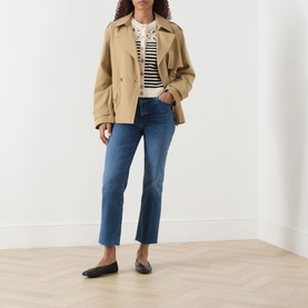 Model wearing FRAME DENIM The Coastal Striped Cardigan in Cream Multi, styled with a camel jacket and blue cropped jeans.