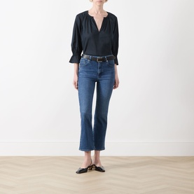 Model wearing FRAME DENIM Crop Boot jeans in Sonnet, a mid-blue wash with slight flare hem, styled with black top and mule shoes.