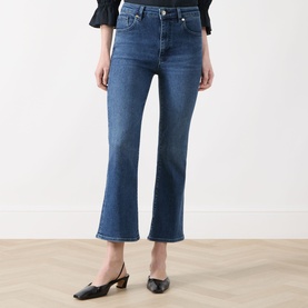 Model wearing FRAME DENIM Crop Boot jeans in Sonnet blue denim, cropped flare leg, styled with black mule heels.