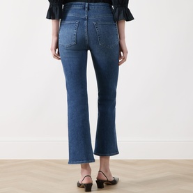 Model wearing FRAME DENIM Crop Boot jeans in Sonnet blue, rear view, cropped flare leg, high waist, styled with black heeled mules.