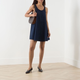 Model wearing FRAME DENIM Duomo mini dress in navy, styled with a brown shoulder bag and black heeled mules.