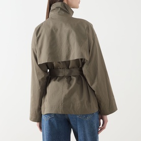 Model wearing FRAME DENIM army cotton jacket, back view, featuring high collar, cape-style yoke, and belted waist, styled with blue jeans.
