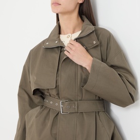 Model wearing FRAME DENIM army green cotton jacket with oversized lapels, chest pockets, and silver eyelet belt, styled with cream blouse.