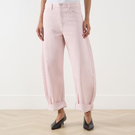 Model wearing FRAME DENIM Taffy pink barrel-leg jeans with cuffed hems, styled with black kitten heel mules.