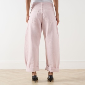 Model wearing FRAME DENIM Taffy jeans in wide-leg barrel fit with cuffed hem, styled with black heeled mules, rear view.