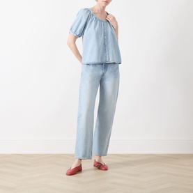 Model wearing FRAME DENIM Haven shirt in light blue with puff sleeves and button front, styled with wide-leg jeans and red flats