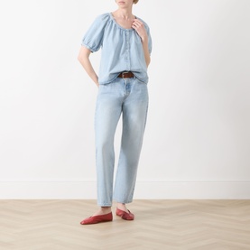 Model wearing FRAME DENIM Haven blue puff-sleeve peasant shirt with light wash jeans, brown belt and red flat shoes