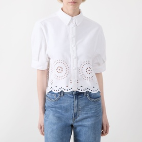 Model wearing FRAME DENIM white cropped shirt with broderie anglaise hem and scalloped edge, styled with blue jeans.