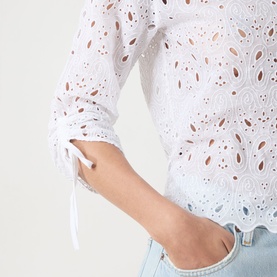 Model wearing FRAME DENIM The Paisley Eyelet Shirt in white, showing close-up of cinch-tie sleeve detail with all-over eyelet broderie, styled with