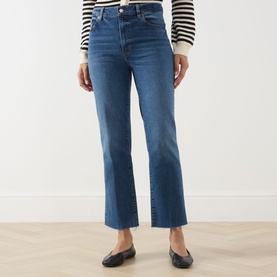 Model wearing FRAME DENIM Straight Jeans in Daylily Raw Fray, mid-blue wash with raw fray hem, styled with black ballet flats and striped top.