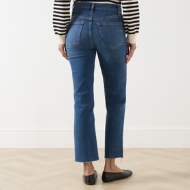 Model wearing FRAME DENIM Straight Jeans in Daylily Raw Fray, cropped hem, rear view, styled with striped top and black ballet flats