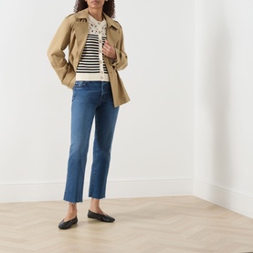 Model wearing FRAME DENIM Straight Jeans in Daylily Raw Fray with a striped top, tan jacket and black loafers.