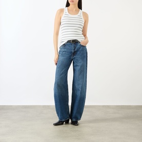 Model wearing FRAME DENIM The Bow High-Rise Wide Leg Jeans in Obscura blue with whiskering detail, styled with a striped white tank top and black