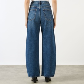 Model wearing FRAME DENIM The Bow High-Rise Wide Leg Jeans in Obscura, showing rear view with five-pocket style and wide barrel leg silhouette.