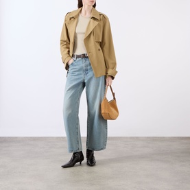 Model wearing FRAME DENIM Coastal straight jeans in light blue denim, styled with a tan cropped trench coat, cream top, and black ankle boots.