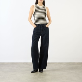 Model wearing FRAME DENIM The Off Duty Drawstring Bow High-Rise Barrel Jeans in Rinse, paired with a black and white striped sleeveless top.