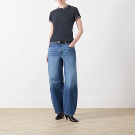 Model wearing Frame Denim navy multi cotton T-shirt with stripe trim, styled with wide-leg blue jeans and black heeled ankle boots.