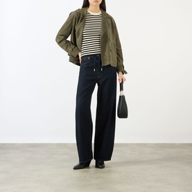 Model wearing FRAME DENIM Coastal Stripe Tank Top in Cream Multi with khaki jacket, wide-leg dark jeans, and black loafers, carrying a small black