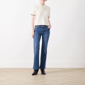 Model wearing FRAME DENIM cream multi short-sleeve polo knit top, styled with mid-blue bootcut jeans and black ankle boots.