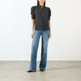 Model wearing FRAME DENIM Gillian Polka Dot Blouse in black multi silk, with puff sleeves and standing collar, styled with wide-leg blue jeans.