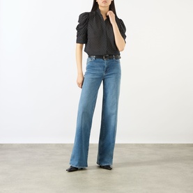 Model wearing FRAME DENIM Gillian Polka Dot Blouse in Black Multi silk, with puff sleeves and standing collar, styled with wide-leg blue jeans.