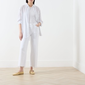 Model wearing FRAME DENIM White Raw Fray Wide Leg jeans with a white tee, striped shirt and yellow flats.