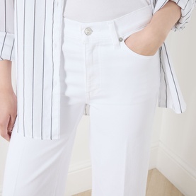 Model wearing FRAME DENIM Wide Leg Jeans in White Raw Fray, styled with a white and navy pinstripe shirt.
