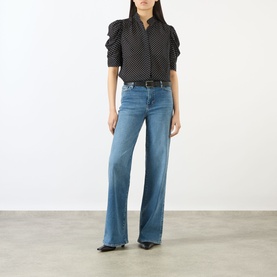Model wearing FRAME DENIM Le Slim Palazzo High-Rise Wide Leg Jeans in Gossamer blue with whiskering detail, styled with black polka dot blouse.