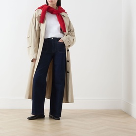 Model wearing FRAME DENIM Le Slim Palazzo Wide-Leg Jeans in Rinse, styled with a beige trench coat, white top and red scarf.