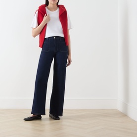 Model wearing FRAME DENIM Le Slim Palazzo Wide-Leg Jeans in Rinse, high-rise wide-cut denim with pressed creases, styled with white tee and red vest