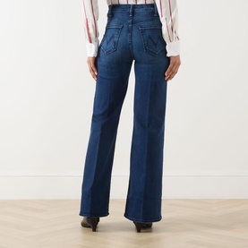 Model wearing Mother Jeans in Homecoming High denim, rear view showing wide-leg flare cut, high waist, styled with a striped shirt and black heels.