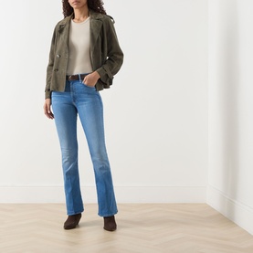 Model wearing Mother Jeans in Piece By Piece, mid-blue bootcut denim, styled with an olive jacket, cream top and dark ankle boots.
