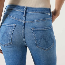 Model wearing Mother jeans in Piece By Piece blue denim, close-up of back pockets with signature stitching detail.
