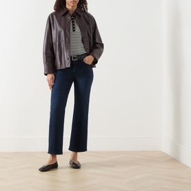 Model wearing Mother jeans in Chip On My Shoulder dark indigo wash, styled with a brown leather jacket, stripe top and black ballet flats.