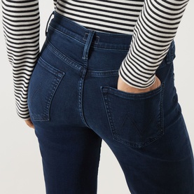 Model wearing Mother jeans in Chip On My Shoulder dark blue denim, rear view, styled with a black and white striped long-sleeve top.