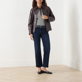 Model wearing Mother Jeans in Chip On My Shoulder dark indigo wash, styled with brown leather jacket, striped polo and black ballet flats.