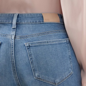 Model wearing Paige Crop Boot jeans in Cinerama blue denim, close-up of back pocket and waistband detail.